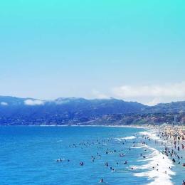 crowded beach scene with many beachgoers playing in the waves